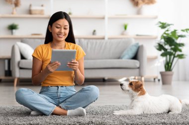 Gülümseyen Japon kadın köpeğinin fotoğraflarını kontrol ediyor, ped kullanıyor.