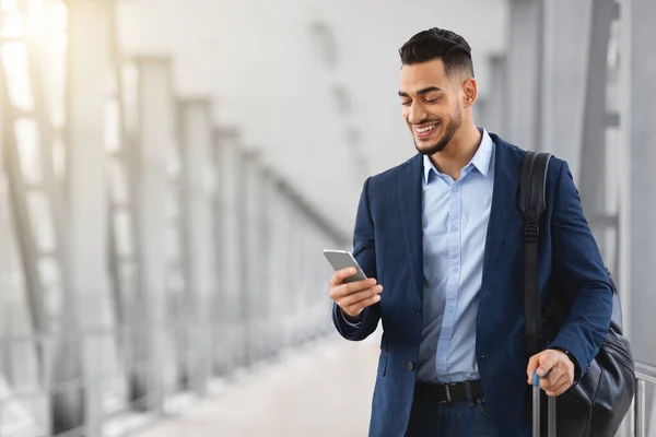Schöner junger arabischer Geschäftsmann benutzt Smartphone, während er am Flughafenterminal steht — Stockfoto