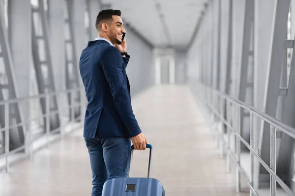 Après l'arrivée. Sourire arabe homme d'affaires parlant sur téléphone portable tout en passant la porte de l'aéroport — Photo