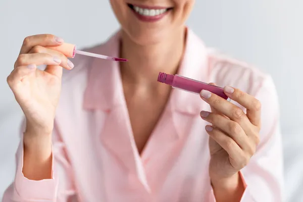 웃는 여인 이 립글로스 봉 튜브를 사용하여 봉합하는 모습 — 스톡 사진