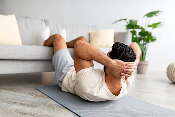 适合在家里瑜伽垫上锻炼腹肌的阿拉伯年轻人。家庭健康概念 — 图库照片