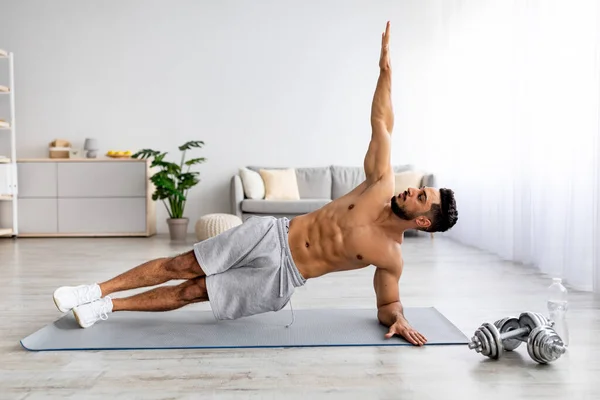 年轻英俊的阿拉伯男子站在瑜伽垫旁边的木板上，复制空间 — 图库照片