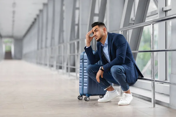 Voo perdido. Homem do Oriente Médio perturbado sentado ao lado da mala no aeroporto — Fotografia de Stock