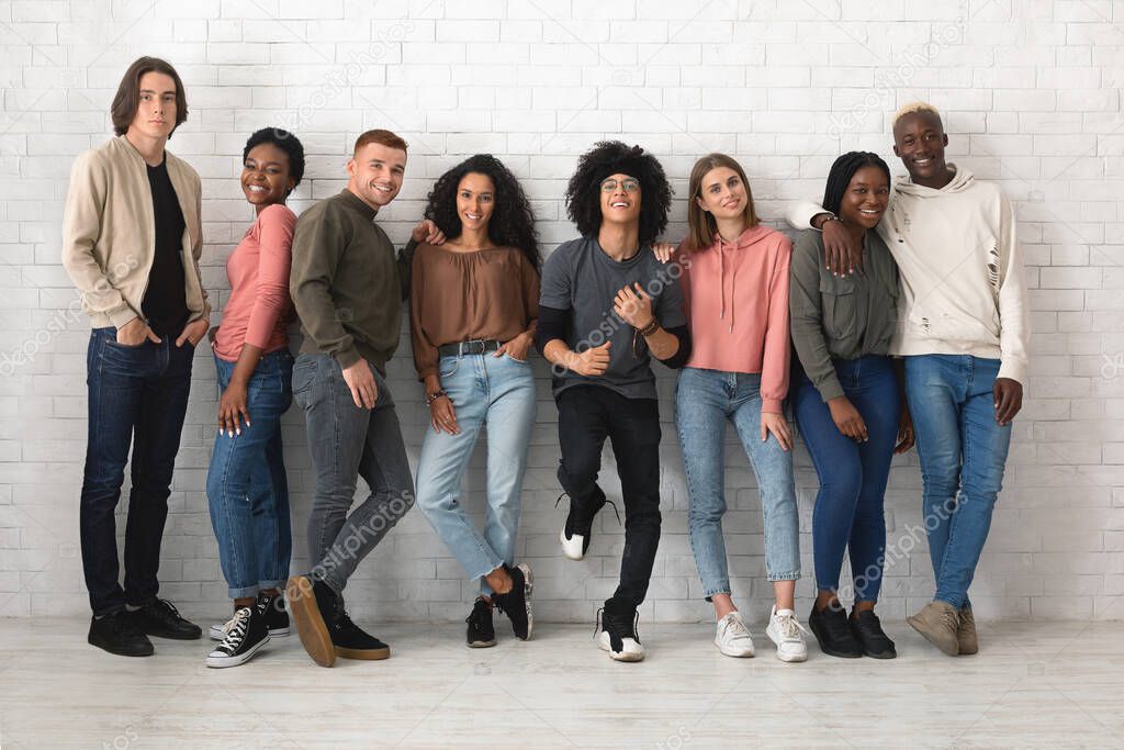 Multiracial group of cheerful young people posing over white
