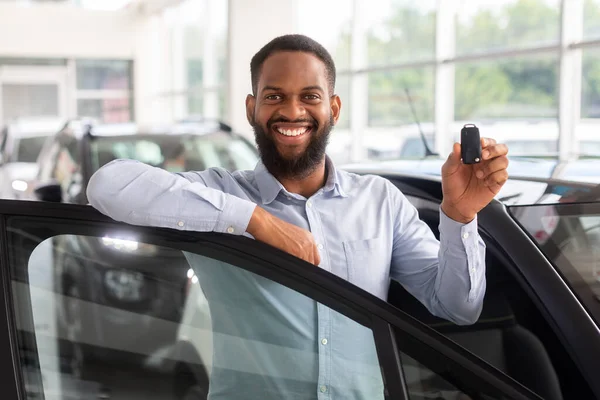 Boldog fekete férfi kocsikulccsal a kezében pózol közel az új autó — Stock Fotó