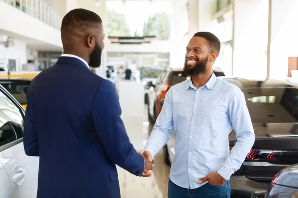 Comprando coche. Retrato del vendedor y el cliente masculino apretón de manos en el centro de concesionario —  Fotos de Stock
