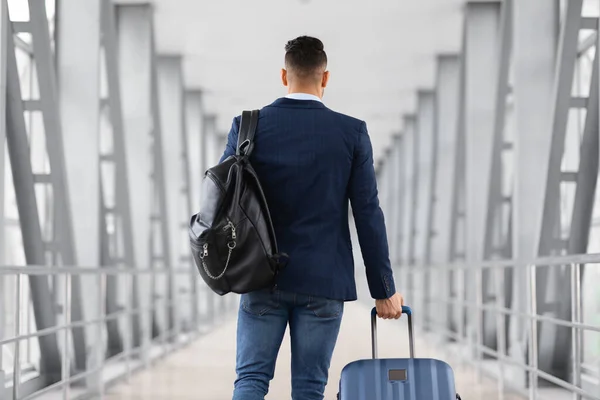 Vista trasera de un viajero masculino irreconocible con mochila y maleta en el aeropuerto — Foto de Stock