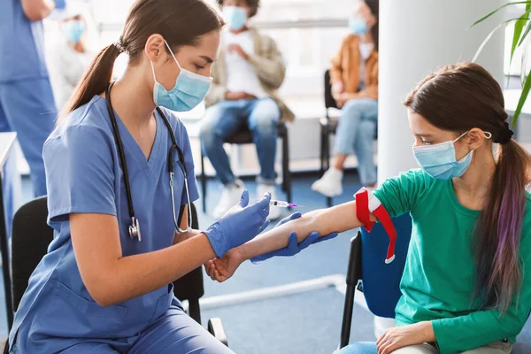Menina usando máscara facial e torniquete médico dando amostra de sangue — Fotografia de Stock