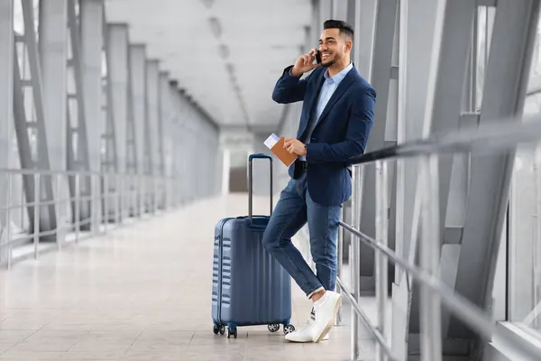 Mobiltelefon. Lächelnder junger Geschäftsmann aus dem Nahen Osten spricht auf dem Flughafen über sein Handy — Stockfoto