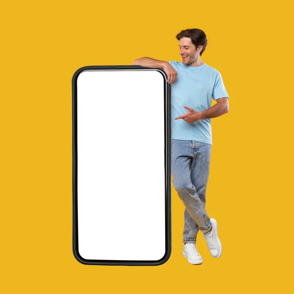 Человек указывает на большой белый пустой экран смартфона, макет — стоковое фото