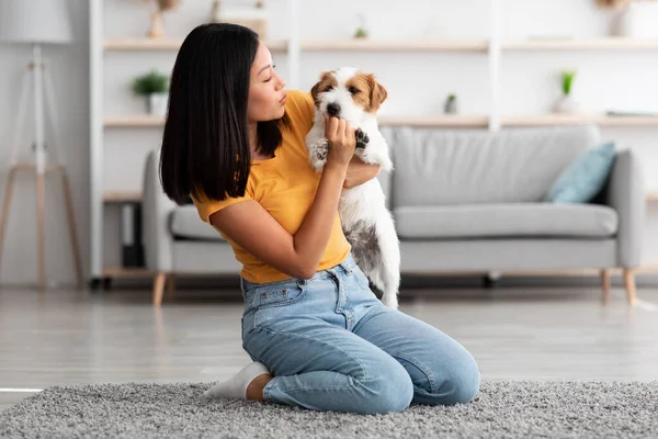 Millennial korean lady cuddling with her puppy at home — Stock Photo, Image