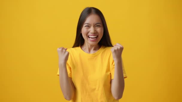 Vreugdevolle Chinese dame Gesturing Ja schudden vuisten over gele achtergrond — Stockvideo