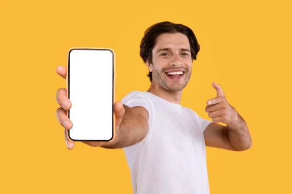 Парень показывает белый пустой экран смартфона и указывает — стоковое фото