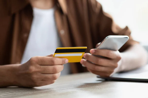 Cartão de crédito amarelo e telefone celular moderno em mãos masculinas — Fotografia de Stock
