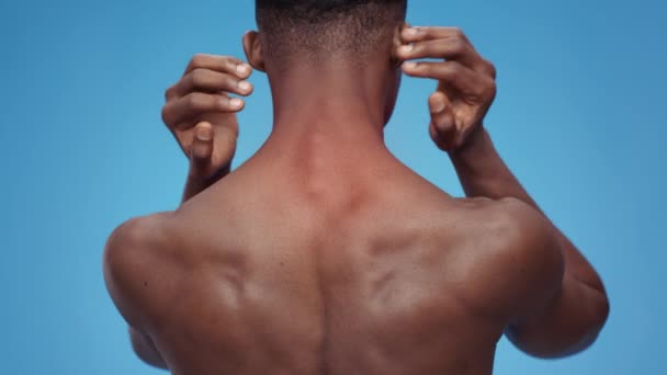 Спортивні травми. Вид ззаду на невизначену сорочку чорний чоловік, який страждає від болю в шиї, масажуючи червону пляму на тілі — стокове відео