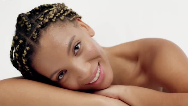 Entspannte Afrikanerin lächelt vor weißem Hintergrund in die Kamera — Stockvideo