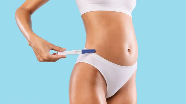 Жінка тримає тест на вагітність в білій нижній білизні — стокове фото