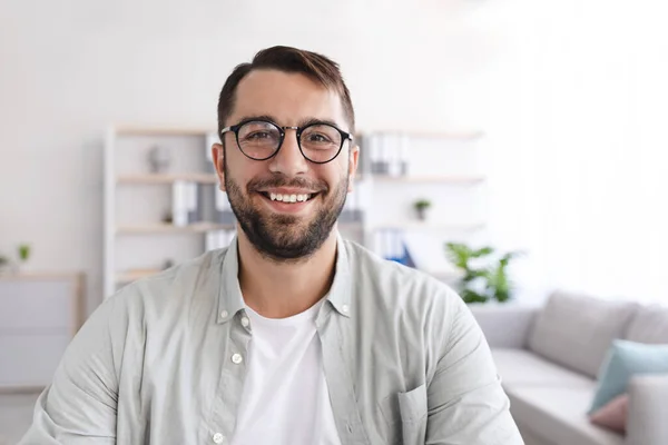 안경을 쓴 쾌활 한 유럽 남자의 머리 사진 최소 거실에서 노트북 웹캠을 보고 — 스톡 사진