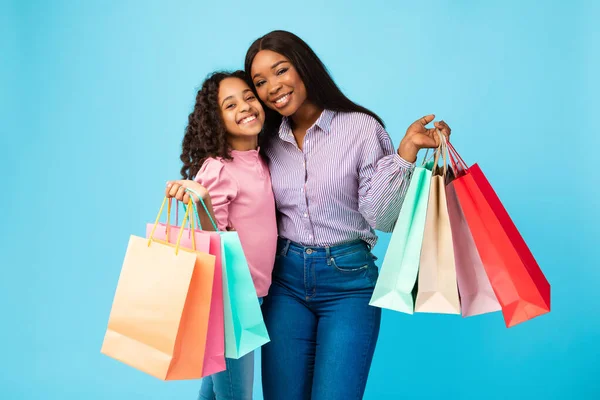 Mujer y chica afroamericanas posando con bolsas de compras —  Fotos de Stock