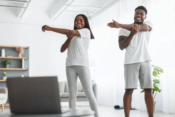 Joven pareja negra haciendo ejercicio de estiramiento de brazos viendo tutorial en línea — Foto de Stock