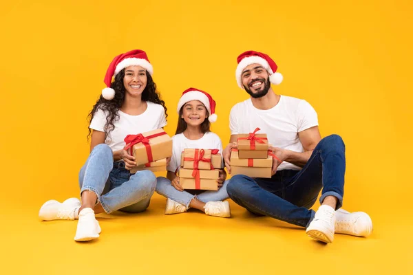 Arab Parents And Little Daughter Holding Christmas Gifts, Yellow Background — Stock Photo, Image