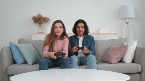 Emocjonalny żonaty mężczyzna i kobieta z joystickami grający w gry wideo razem w domu, kobieta tracąca mężczyznę cieszącego się zwycięstwem — Wideo stockowe