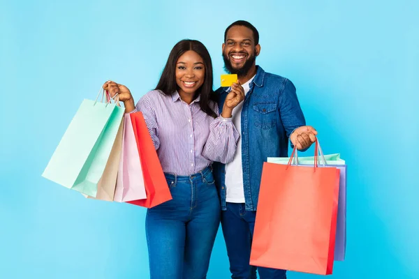 Retrato de feliz pareja negra sosteniendo tarjeta de crédito y bolsas —  Fotos de Stock