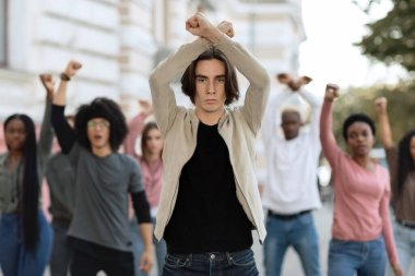 Çok ırklı aktivistlerin lideri genç adam yumruklarını çaprazlıyor.