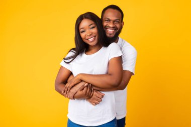 Afrikalı Amerikalı sakallı adam kadınına sarılıyor.
