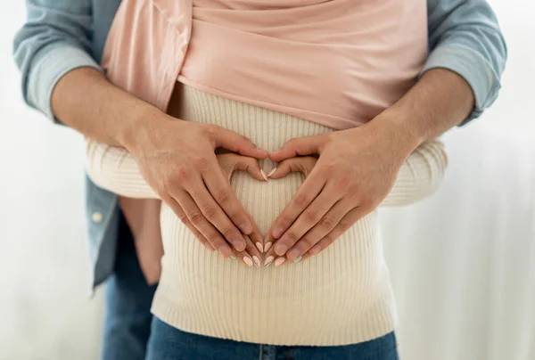 Nahaufnahme der muslimischen schwangeren Frau und ihr Mann umarmen Bauch zusammen, machen Herz mit ihren Händen — Stockfoto