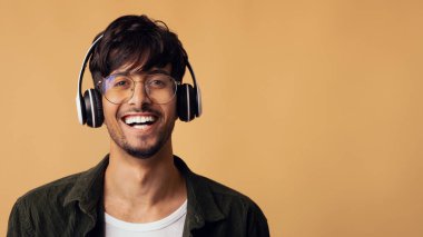 Gülen Arap adam yeni kablosuz kulaklığın keyfini çıkarıyor.