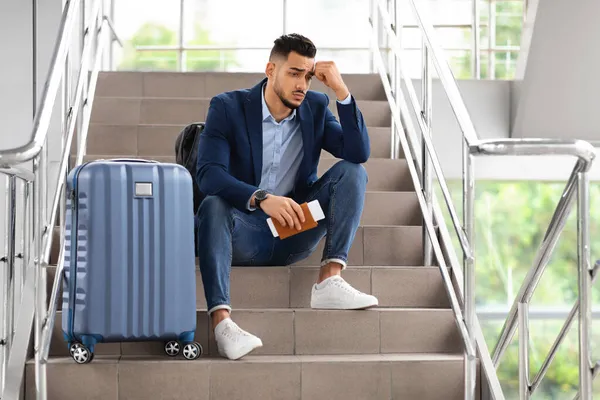 Tipo de Oriente Medio trastornado sentado en las escaleras de la terminal del aeropuerto con equipaje — Foto de Stock