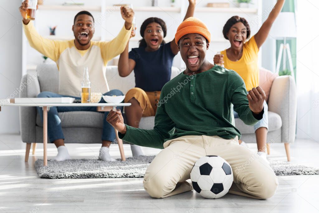 Happy african american football fans watching match on TV