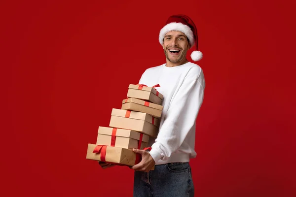 Vente de Noël. Jeune homme excité dans Santa Hat posant avec des boîtes-cadeaux — Photo