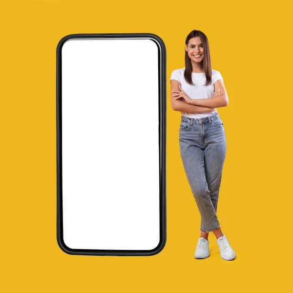 Frau steht neben großem weißen, leeren Smartphone-Bildschirm — Stockfoto