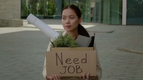 Infeliz asiático hembra buscando trabajo holding cartón caja al aire libre — Vídeo de stock