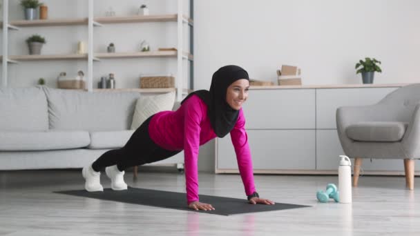 Entrenamiento cardiovascular. Joven mujer positiva de Oriente Medio practicando ejercicio de escalador, haciendo ejercicio en el suelo en casa — Vídeo de stock