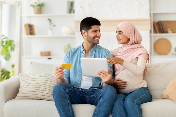 Terhesség és online vásárlási koncepció. Muszlim terhes házastársak digitális táblagéppel és hitelkártya-vásárlási termékekkel — Stock Fotó