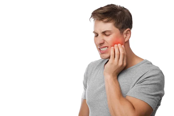 Triste infeliz jovem bonito caucasiano sofrendo de dor de dente, pressiona mão a bochecha, destacado em vermelho — Fotografia de Stock
