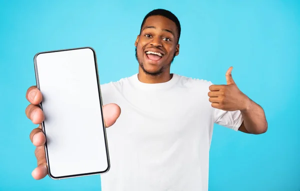 Емоційний чорний чоловік демонструє смартфон з порожнім екраном — стокове фото