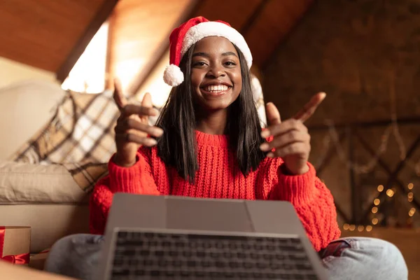 Glad svart kvinna i Santa hatt gör videosamtal med bärbar dator, hälsning familj med jul eller nyår hemifrån — Stockfoto