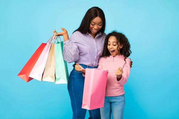 Afro-americana mujer y chica buscando iside bolsas de compras —  Fotos de Stock
