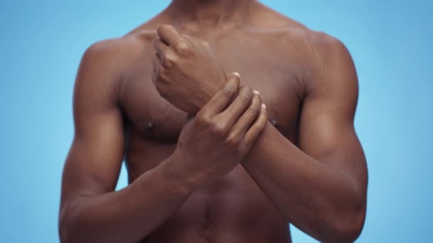 Carpal tunnel syndrome. Unrecognizable shirtless african american man massaging painful wrist, blue studio background — Stock Video