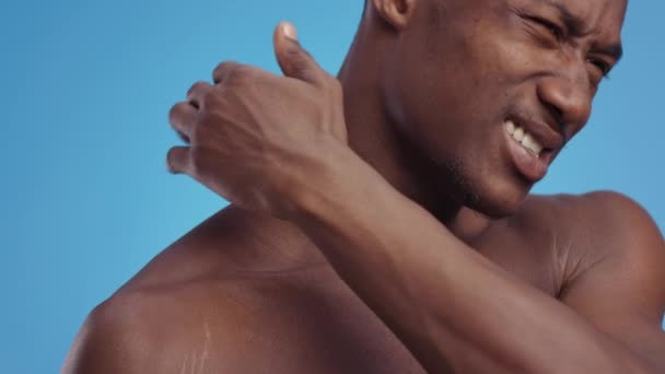 Ból mięśni. Młody, afrykański mężczyzna bez koszuli cierpiący na zapalenie szyi, masujący ciało i marszczący brwi — Wideo stockowe