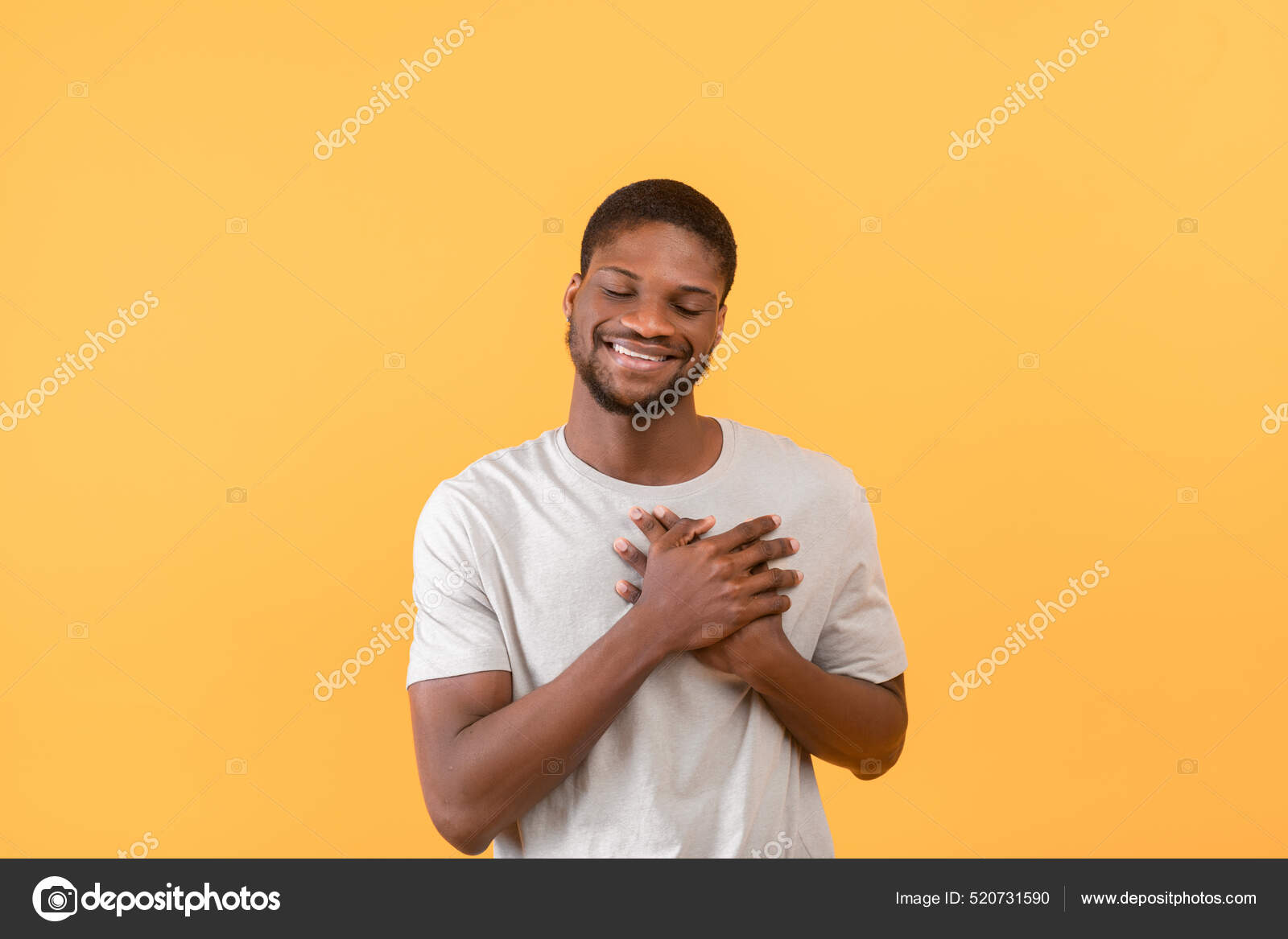 Сердечный черный парень держит руки на груди, выражая благодарность и  положительные эмоции, желтый фон стоковое фото ©Milkos 520731590