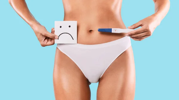 Sad woman holding positive pregnancy test wearing white underwear