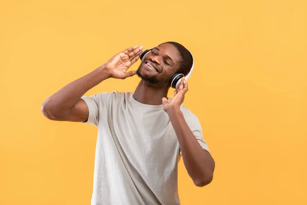 Найкраща музика. Щасливий американський афроамериканець у бездротових навушниках, який любить свої улюблені пісні і посміхається — стокове фото