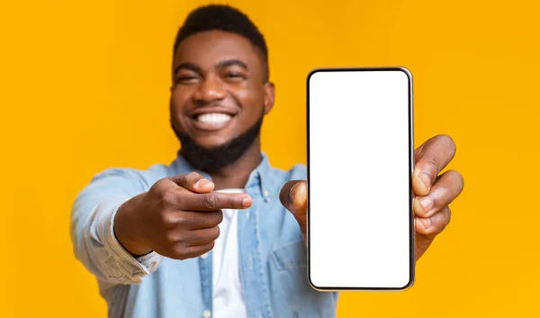 Улыбающийся африканский американец указывает на сотовый телефон с пустым экраном — стоковое фото