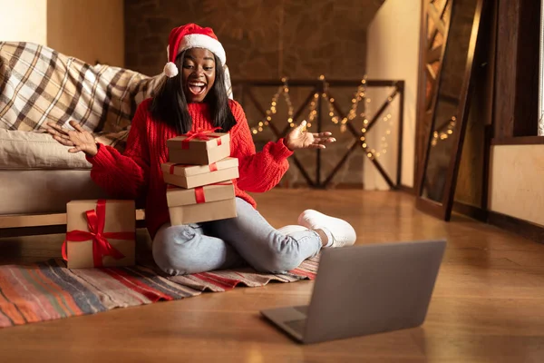 Xmasの贈り物の上に興奮を表現する千年の黒人女性,クリスマスに自宅からラップトップでチャットビデオ — ストック写真