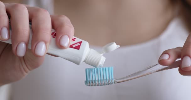Mujer exprimiendo pasta de dientes en el cepillo de dientes en casa — Vídeo de stock